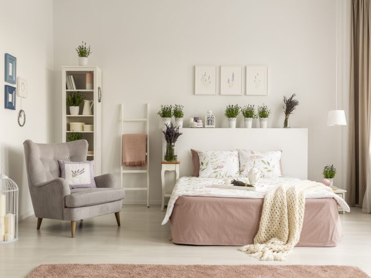 Real photo of a feminine bedroom interior with a comfy armchair,